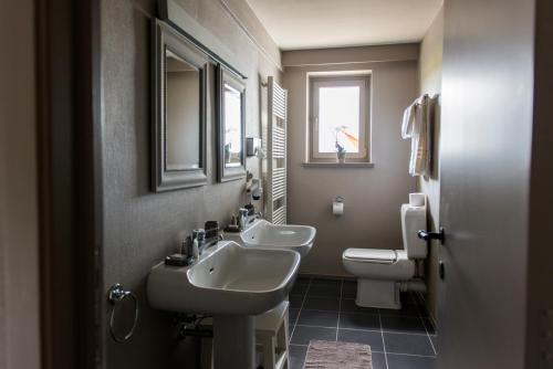 a bathroom with two sinks and a toilet and a window at Lebeau 19 Hotel in Knokke-Heist