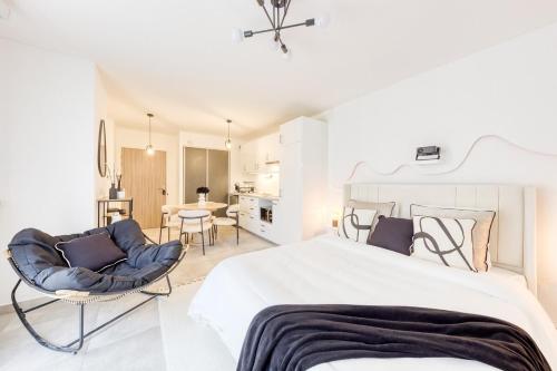 a white bedroom with a large bed and chairs at Studio Chic avec Cinéma Privé À 15 min de Disneyland et 20 min de Paris in Champs-Sur-Marne