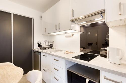 a kitchen with white cabinets and a counter top at Studio Chic avec Cinéma Privé À 15 min de Disneyland et 20 min de Paris in Champs-Sur-Marne