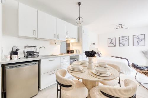 a white kitchen with a table and chairs at Studio Chic avec Cinéma Privé À 15 min de Disneyland et 20 min de Paris in Champs-Sur-Marne