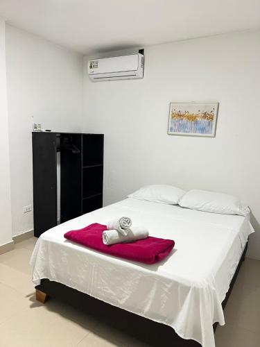 a bedroom with a white bed with a red blanket at Tropical Dreams in San Andrés