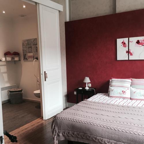a bedroom with a bed and a red wall at B&B Le Notaire in Bomal