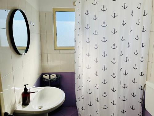 a bathroom with a sink and a shower curtain with anchors at EasySleep City Center in Divjakë