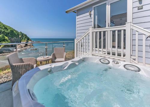 a hot tub on a balcony with a view of the ocean at Beach Cove Coastal Retreat in Ilfracombe