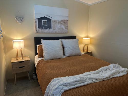 a bedroom with a bed with two lamps on tables at Lazy Acre in Hakaru