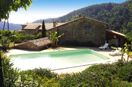 a small swimming pool in front of a house at Charming stone house with shared pool, Chambonas in Chambonas