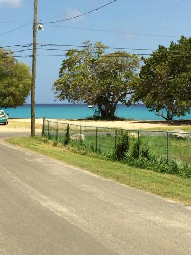 a road with a fence and trees and the ocean at Georges Royal Inn in Frederiksted