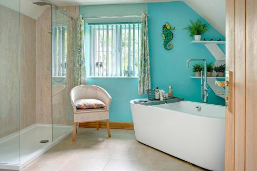 a bathroom with a tub and a chair and a sink at Stunning Cotswold Cottage Nr Country & River Walks in North Cerney