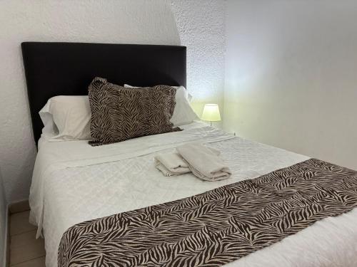 a bed with a black and white blanket and pillows at Extraordinario departamento in Guadalajara