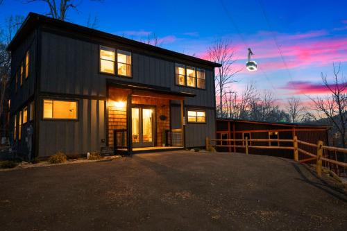 a black house with a fence and a sunset at Luxury Gatlinburg Cabin, Heated Pool, Theater, Hot Tub in Gatlinburg