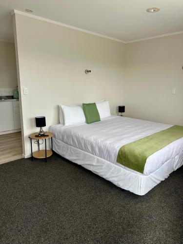 a bedroom with a large white bed with two lamps at Bay Lodge Motel in Tauranga