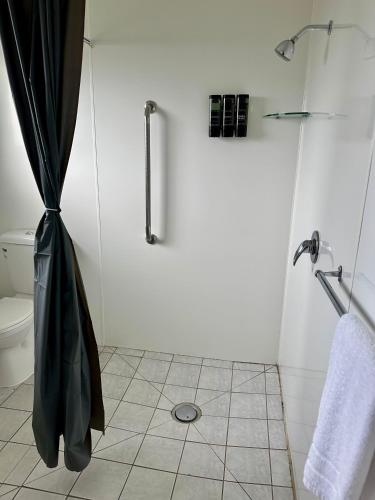 a bathroom with a shower with a black shower curtain at Bay Lodge Motel in Tauranga