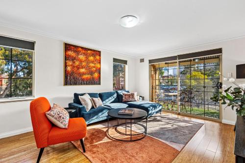 a living room with a blue couch and orange chairs at The Bishops Escape A Sepal Stay in Perth