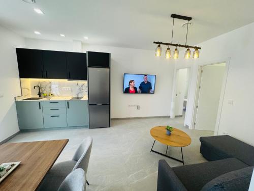 a kitchen and living room with a table and a tv at Calpe apartamento LuXurY nuevo playa centrico parking wifi aire piscina patio in Calpe