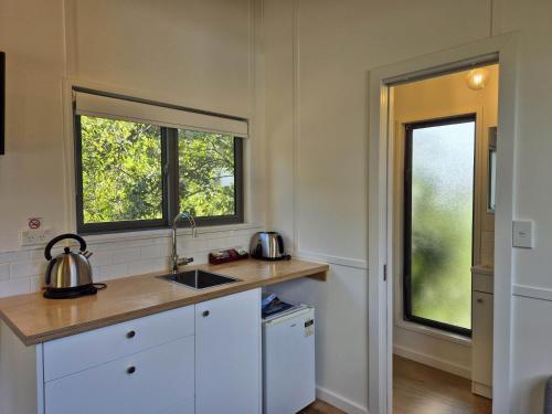 a kitchen with a counter and two windows at Punakaiki Beach Camp in Punakaiki
