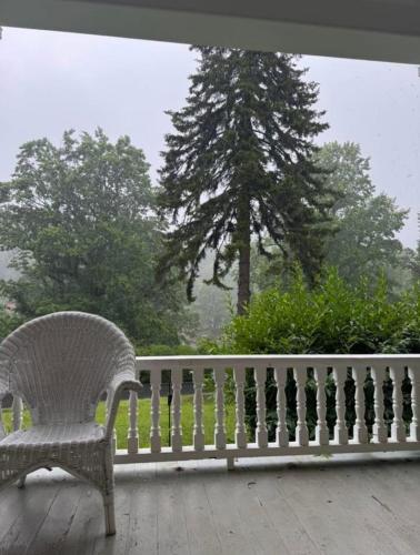 a white chair sitting on a porch with a tree at The Balsam Mountain Inn in Sylva