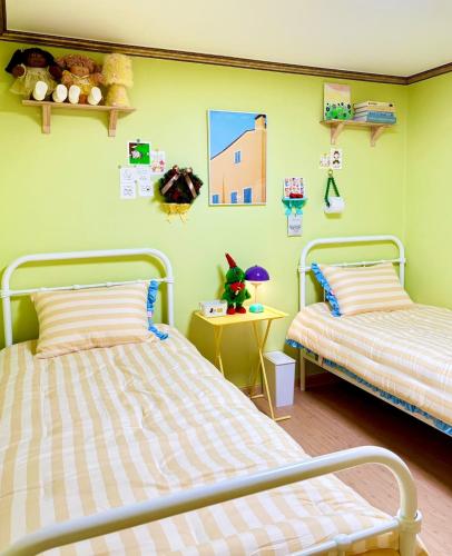 two beds in a room with green walls at Daegu Gyeongsan Stay in Gyeongsan