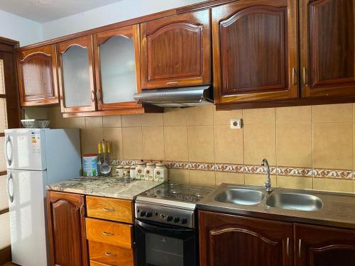 una cucina con mobili in legno, un lavandino e un frigorifero di Apartamento em Monte a Mindelo