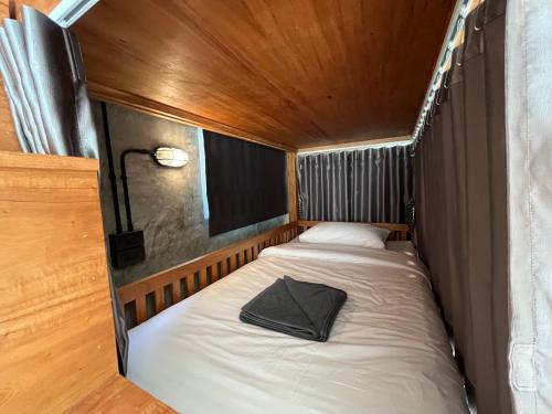 a small bed in a small room with a lamp at Friendlyhostel in Khao Sok