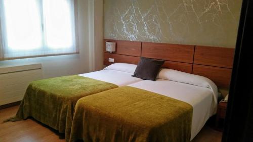 Hotel Rural Neixon في بويرو: غرفة فندق بسريرين في غرفة نوم