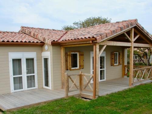 une maison avec une terrasse et un toit dans l'établissement Chalet 3 chambres avec piscine chauffée, proche Lac du Jaunay et plages de Saint-Gilles-Croix-de-Vie - FR-1-783-23, à La Chapelle-Hermier