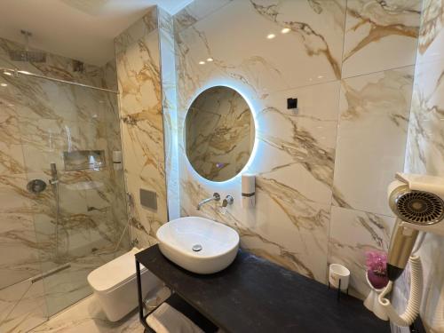a bathroom with a sink and a shower at The Queen's Lion Premium HOTEL in Sarandë