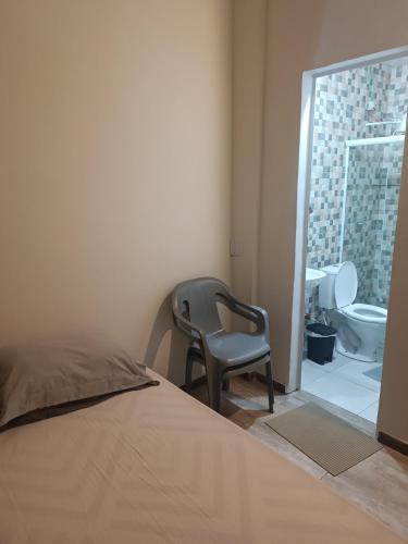 a bedroom with a chair and a bathroom with a shower at Assel Estudios in Curitiba