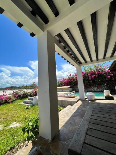 a white pergola with a pool and flowers at Malcom Ocean View Retreat in Pongwe