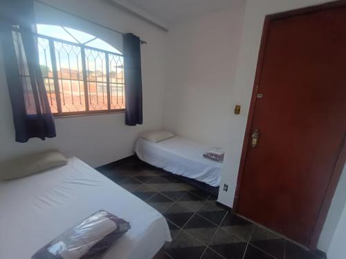 a small room with two beds and a window at Residence Efrata Casa Inteira in Itaboraí