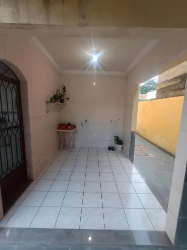 an empty room with a white tile floor and a door at Residence Efrata Casa Inteira in Itaboraí