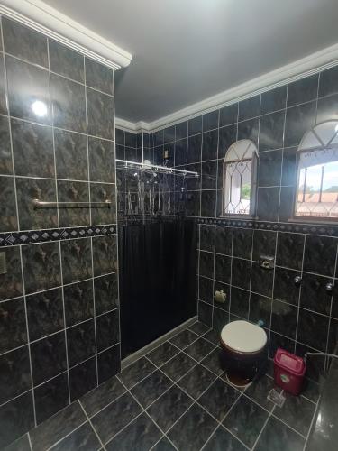 a bathroom with a black tiled shower with a toilet at Residence Efrata Casa Inteira in Itaboraí