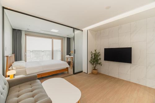 a bedroom with a bed and a tv on a wall at Jeju The Terrace View in Jeju