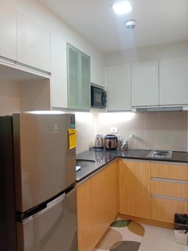 a kitchen with white cabinets and a stainless steel refrigerator at 8 Newtown Mactan Condominium in Lapu Lapu City