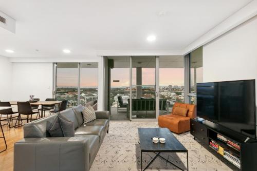 a living room with a couch and a television at EAST34 - Skyline Haven East Perth in Perth