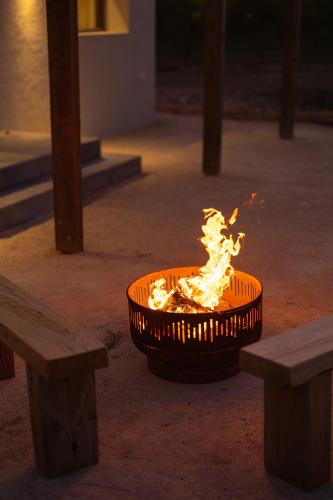 a fire burning in a basket next to two benches at Stone - Rare Earth Retreats in McLaren Vale
