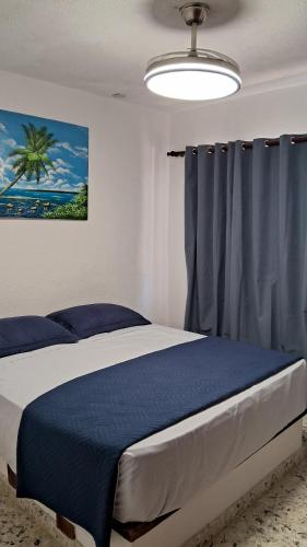a bedroom with a bed with blue sheets and a window at CortLang Vacation Rentals, Costambar in San Felipe de Puerto Plata