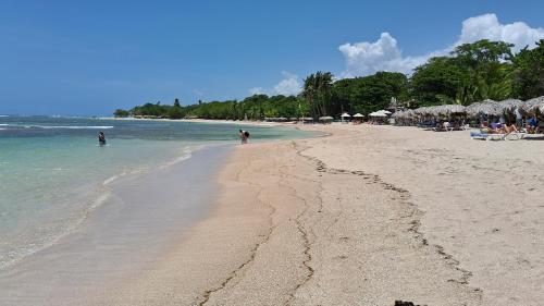 a beach with people swimming in the ocean at CortLang Vacation Rentals, Costambar in San Felipe de Puerto Plata