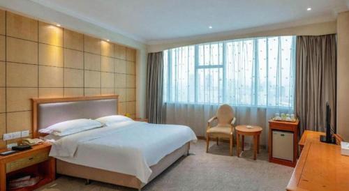 a bedroom with a bed and a desk and a window at Jincheng Pacific Hotel in Jincheng