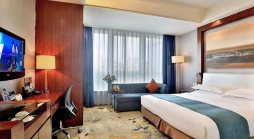 a hotel room with a bed and a desk and a television at Jinhua World Trade Hotel in Jinhua