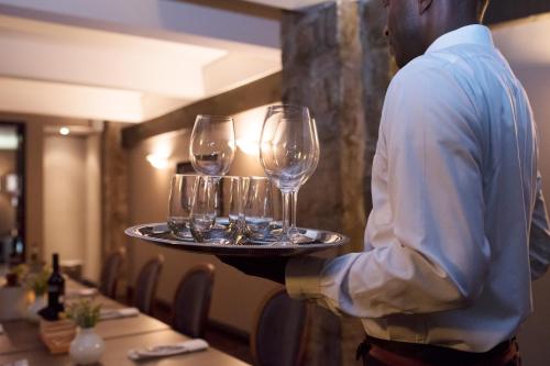 a man holding a tray with wine glasses on it at Old Stone Inn Boutique Hotel in Niagara Falls