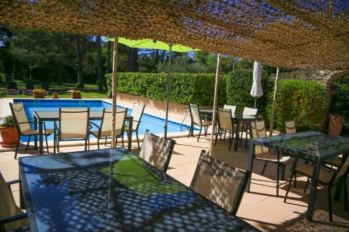 un patio avec tables et chaises et une piscine dans l'établissement Mas la Provence, à LʼIsle-sur-la-Sorgue