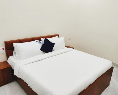 a large bed with white sheets and pillows at Rkr Residency in Farrukhnagar