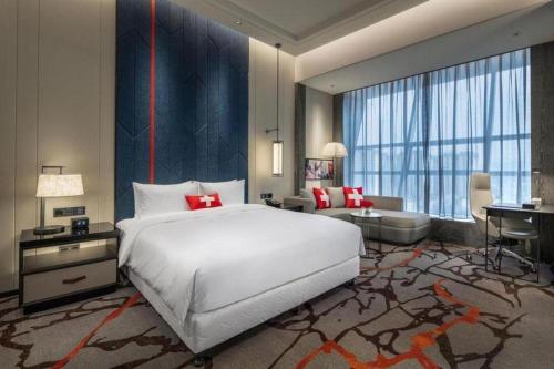 een slaapkamer met een groot wit bed en een bureau bij Swisstouches Hotel Ankang in Ankang