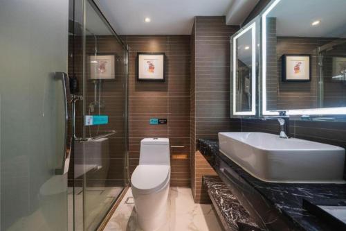 a bathroom with a sink and a toilet and a mirror at Xana Hotelle Xiamen Airport Zone Government in Xiamen