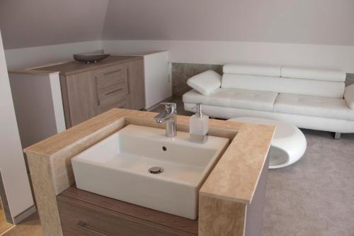 a bathroom with a sink and a living room with a couch at Villapark Luxury Apartman Balatonfüred in Balatonfüred