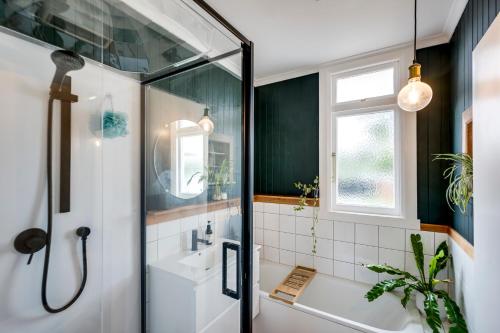 a bathroom with a shower and a tub and a sink at Bungalow on Chambers in Napier