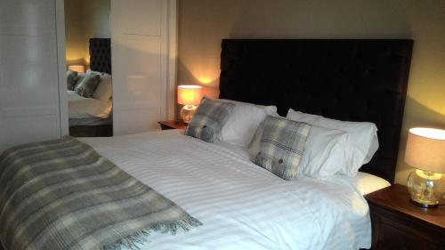 奧尼赫的住宿－Allt Nan Ros Apartments fort william，卧室配有一张带白色床单和枕头的大床。