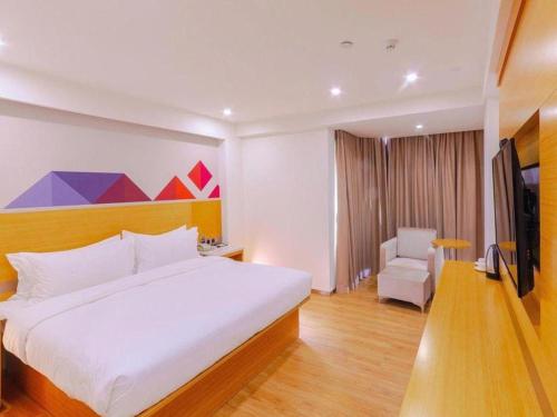 a bedroom with a large white bed and a chair at Borrman Hotel Zhanjiang Shimao Building High-speed Railway Station in Zhanjiang