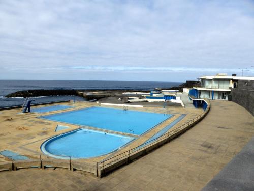 a large swimming pool with the ocean in the background at Azorean Sunset Loft 2 in Ribeira Grande