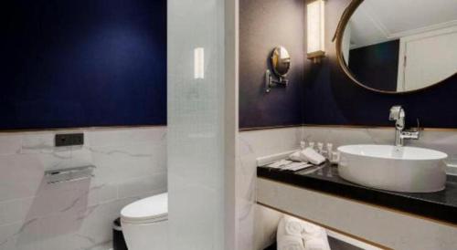 a bathroom with a sink and a toilet and a mirror at James Joyce Coffetel Harbin West High-speed Railway Station Wanda Plaza in Harbin